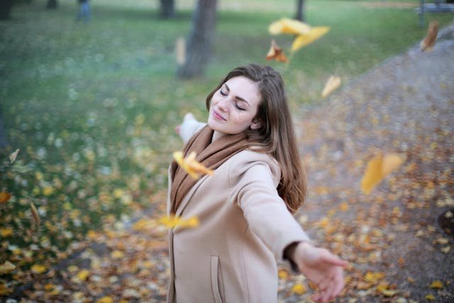 Image of a woman enjoying falling leaves, symbolizing the beauty of noticing everyday wonders. Wilson Counseling in Texas can help you discover the power of delight for a more fulfilling life.