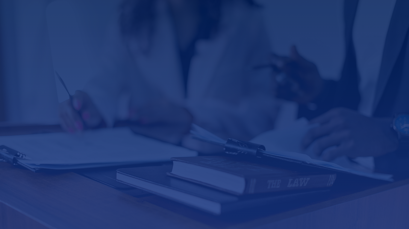 A person wearing a white lab coat is writing on a notepad, with a book titled 'The Law' on the table beside them.