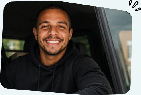 Smiling male heating engineer sitting in the driver's seat of a vehicle, looking out the window.