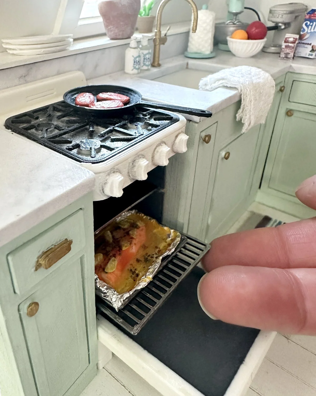 Miniature kitchen scene with a stove, countertop, and tray.