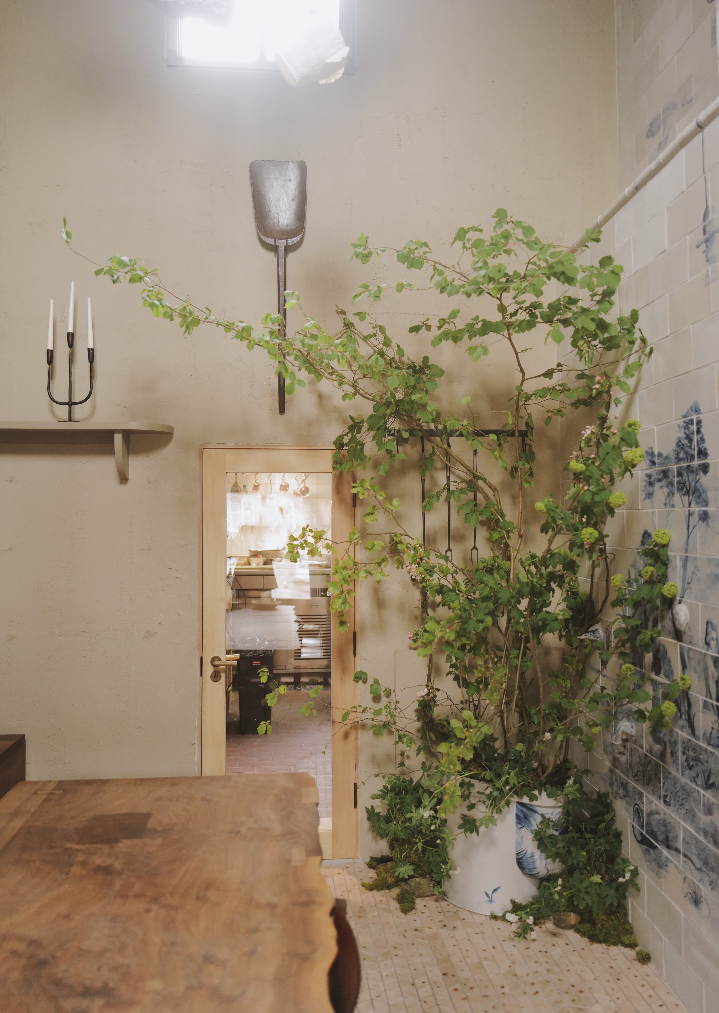 Interior room with wooden table, potted plant, wall decor, and doorway to another room