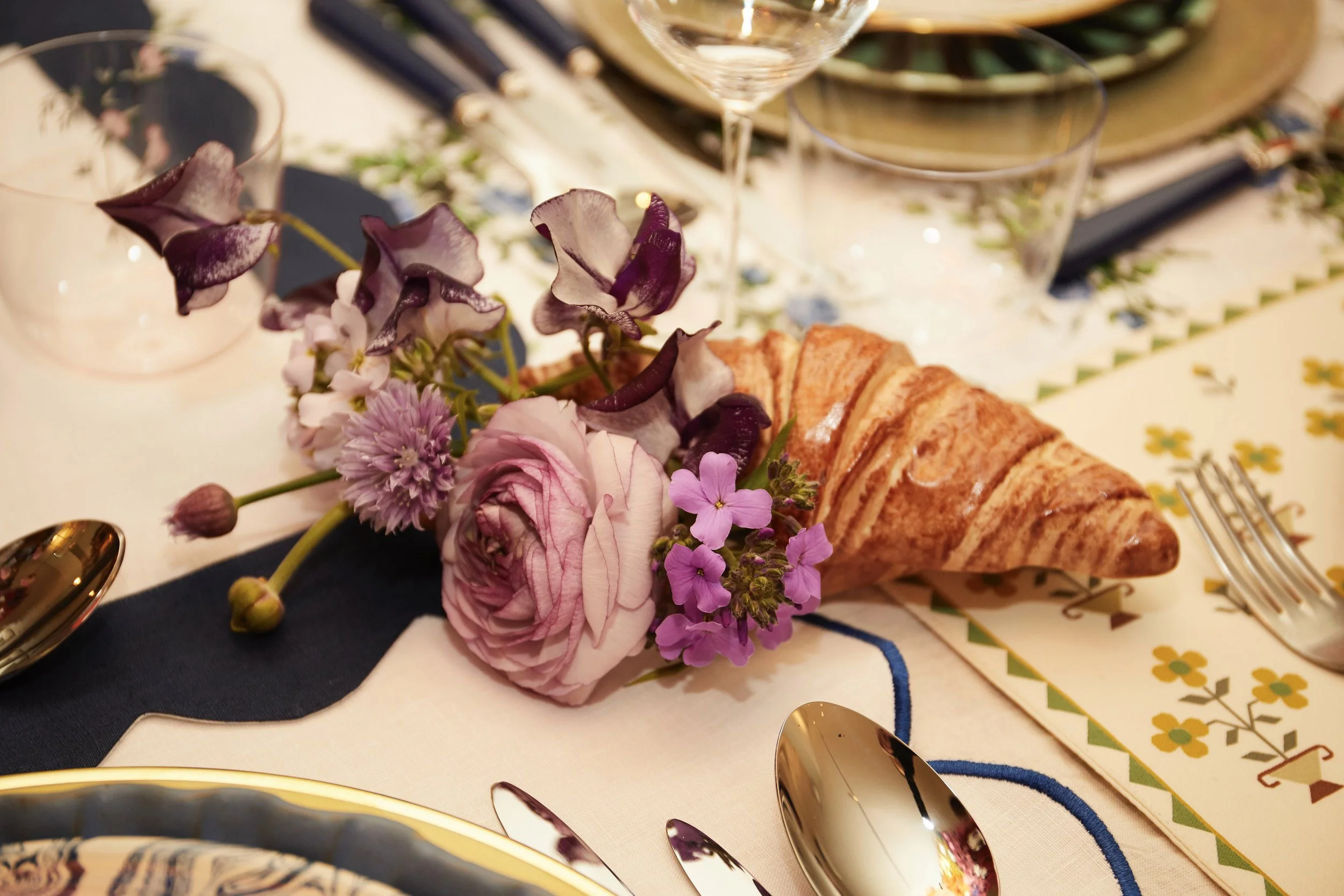 Elegant table setting with purple flowers and a croissant centerpiece