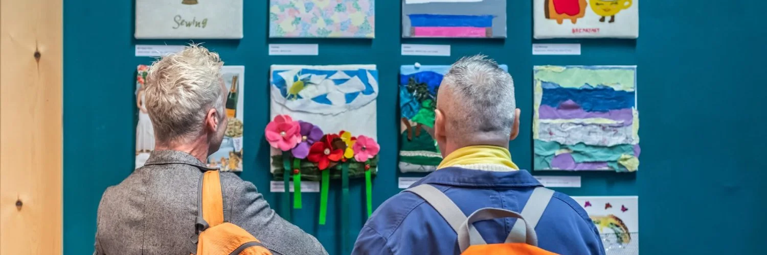 Two people seen from behind looking at canvas artworks.
