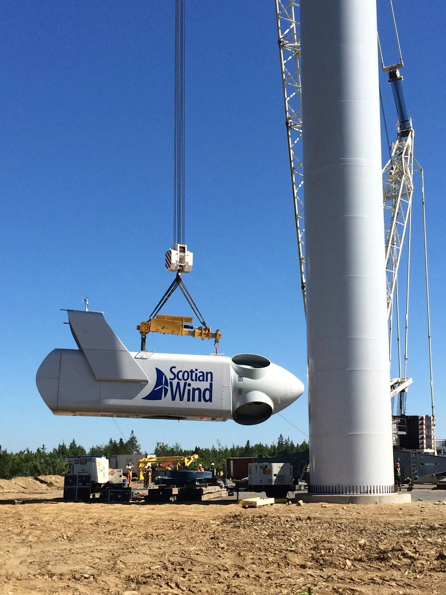 Construction team installing a large wind turbine blade with the Scotiabank Wind logo visible, under a clear blue sky.