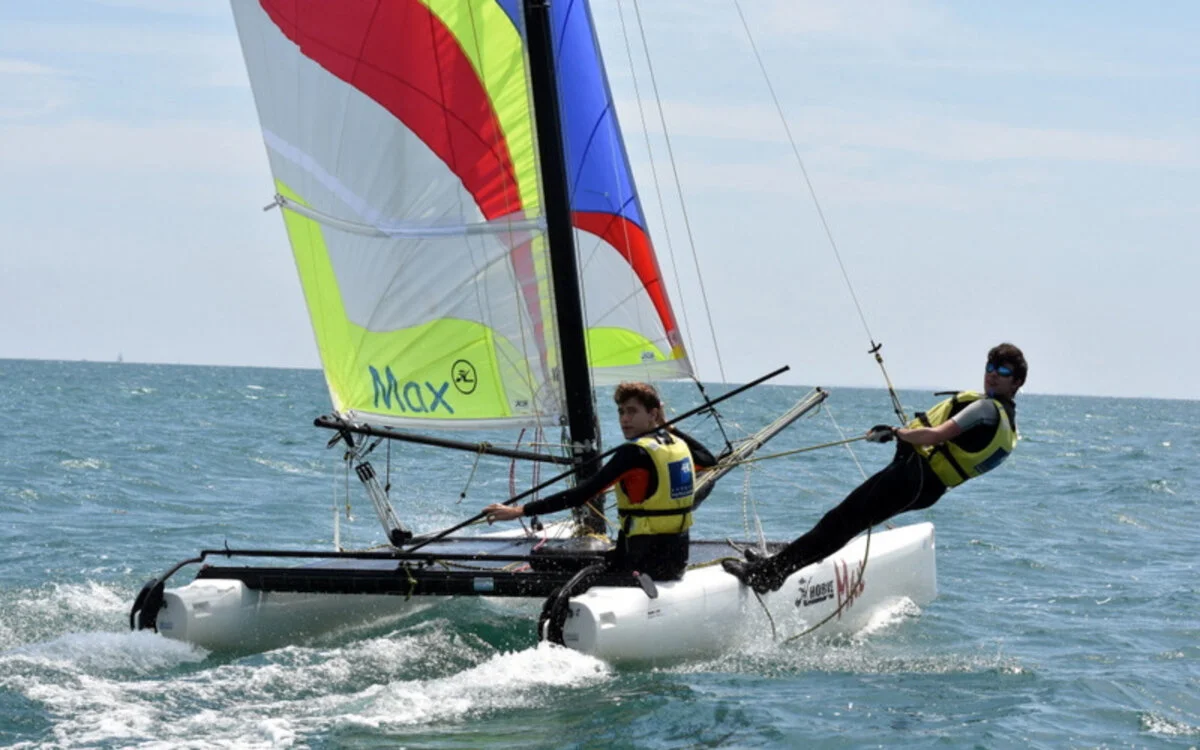 A catamaran with colourful sails sailing off the coast of Carnac, in Quiberon Bay