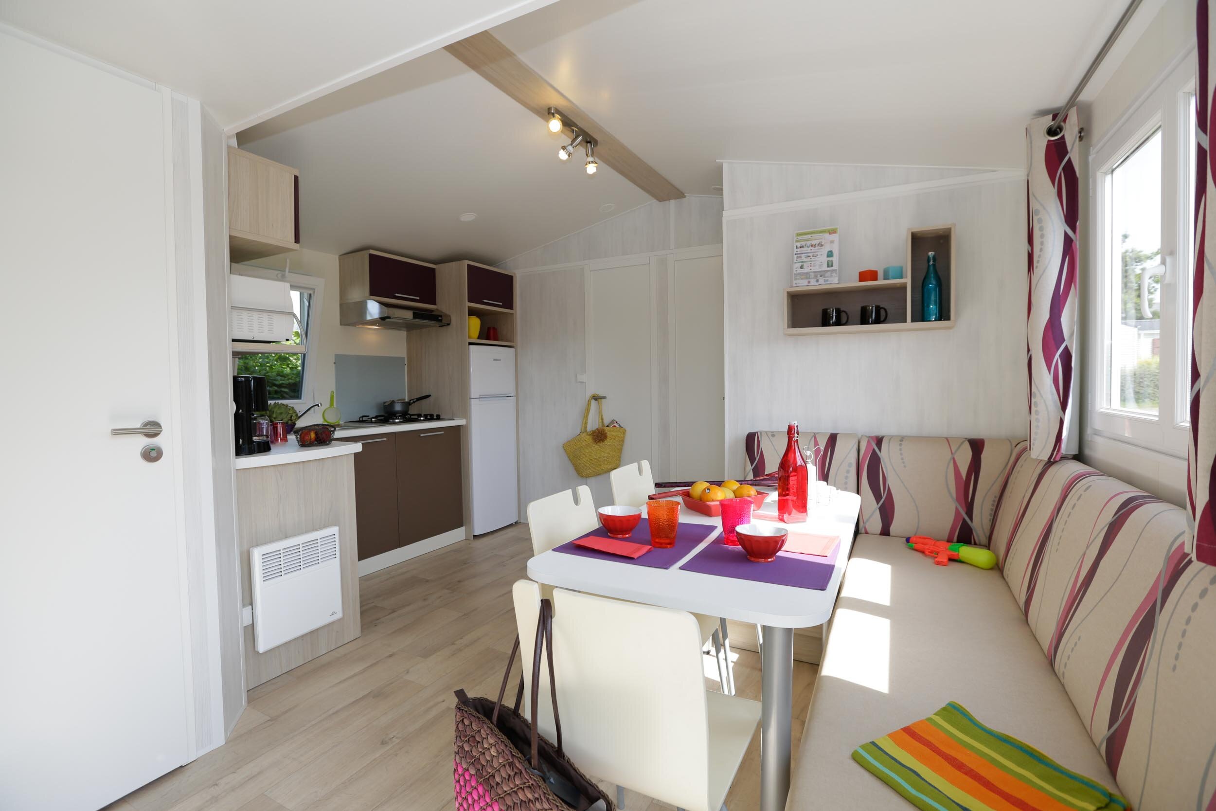 Intérieur d'un mobil-home du Camping Les Druides : cuisine équipée et coin repas lumineux