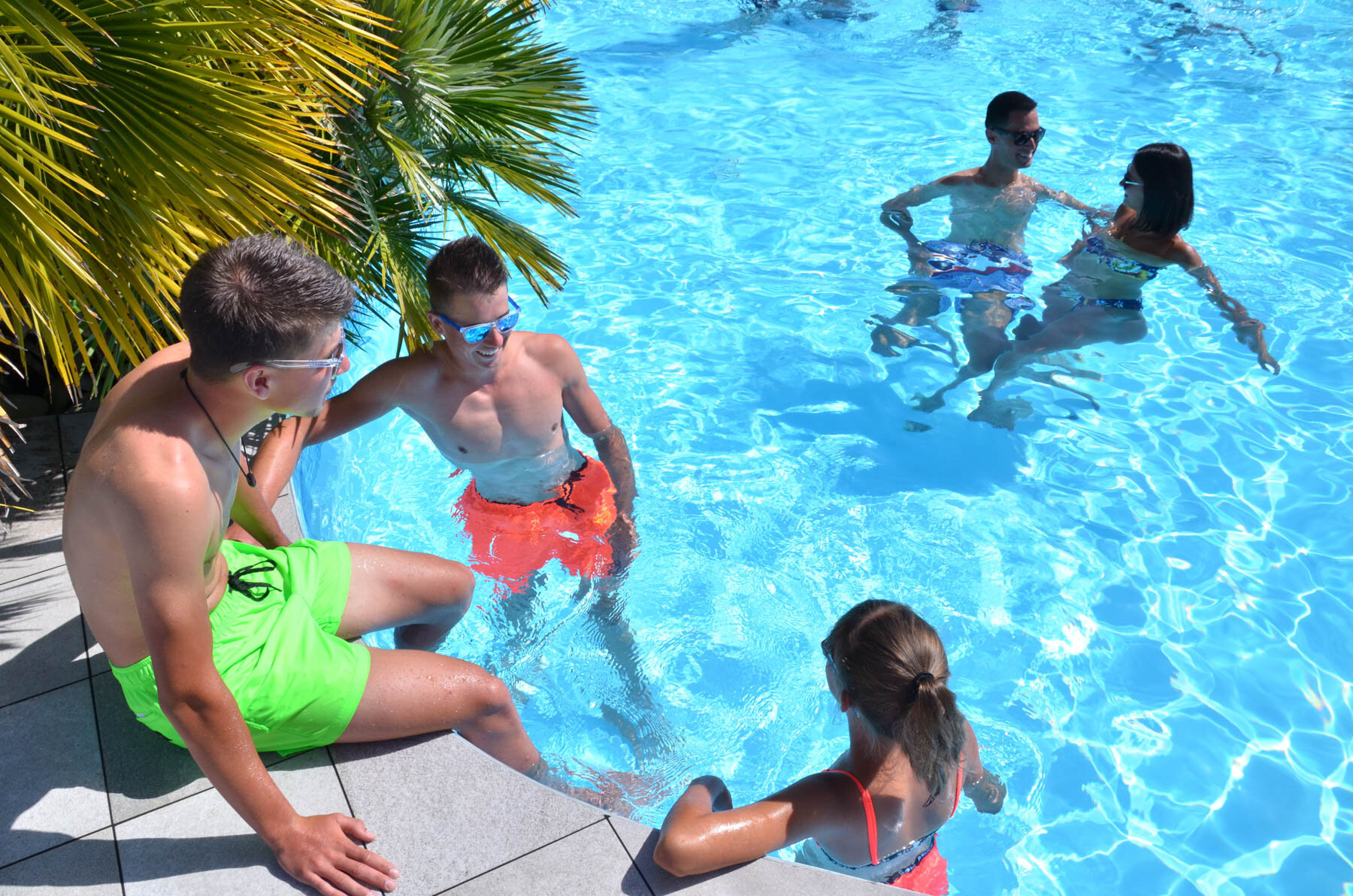 Jeunes vacanciers dans la piscine chauffée du Camping Les Druides par une journée ensoleillée