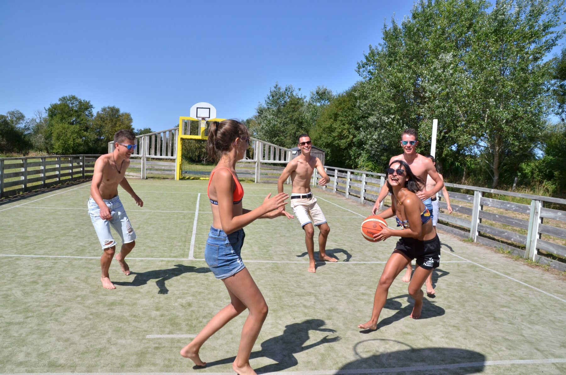 Jeunes vacanciers jouant au basket pieds nus sur le terrain multisports du Camping Les Druides à Carnac