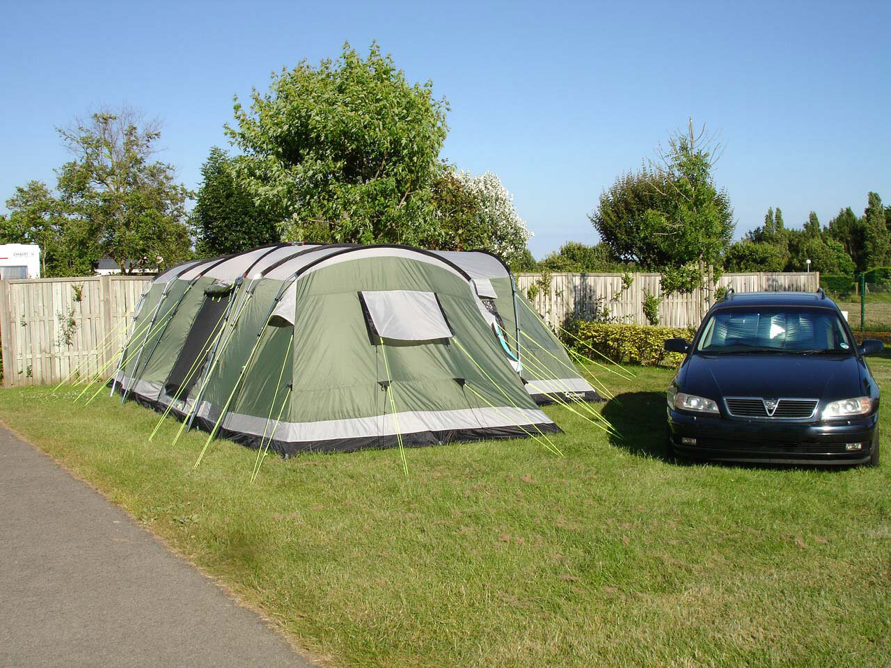 Grande tente familiale et voiture sur un emplacement ombragé du Camping Les Druides