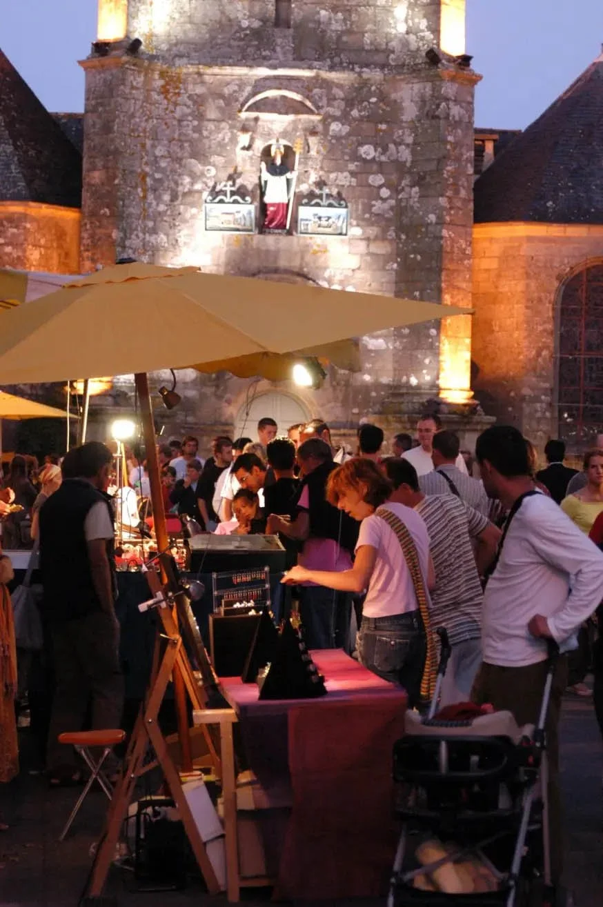 Craft stalls in front of the illuminated church during the Carnac night market