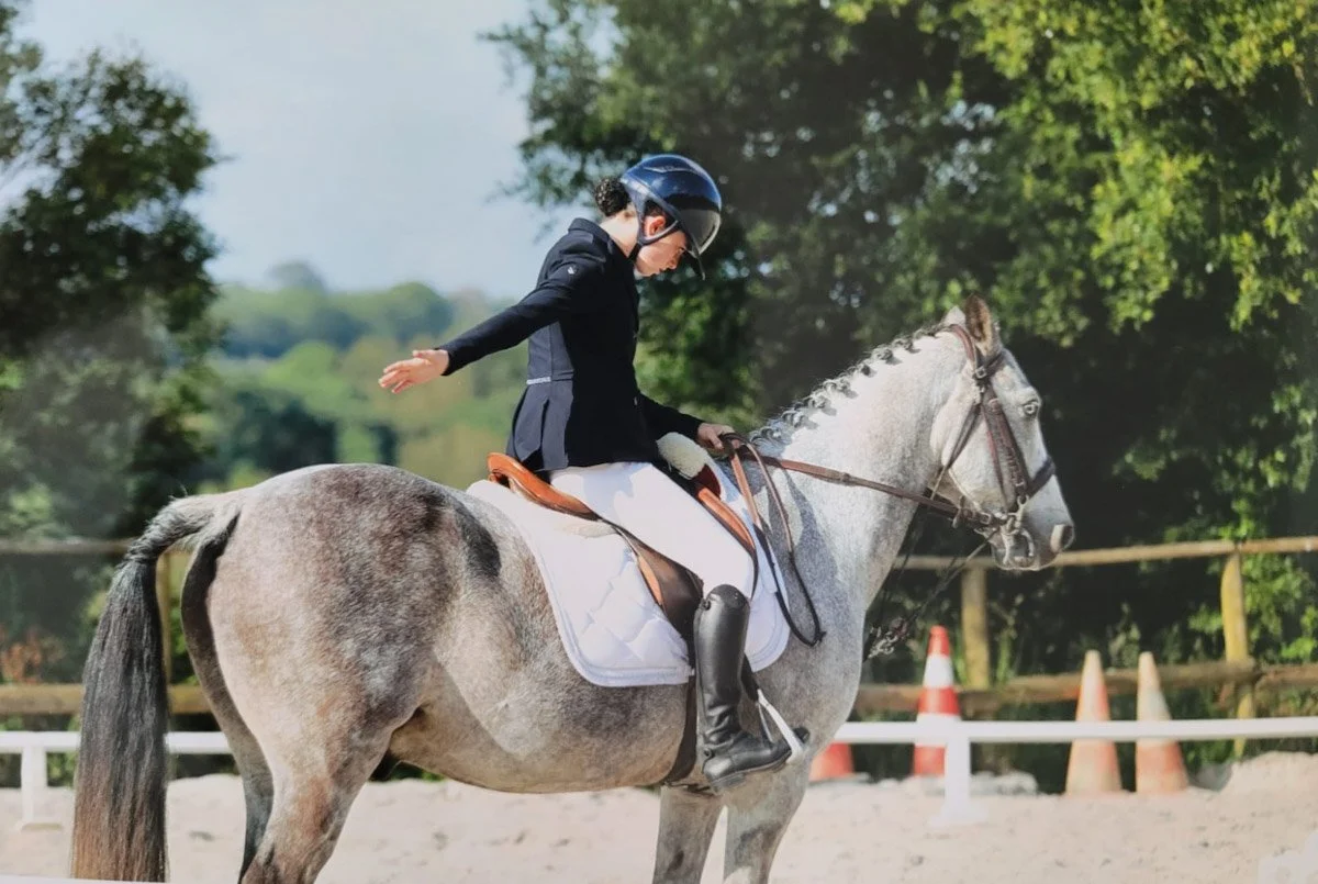 A rider on a grey horse in the arena at the Centre Équestre des Menhirs, Carnac