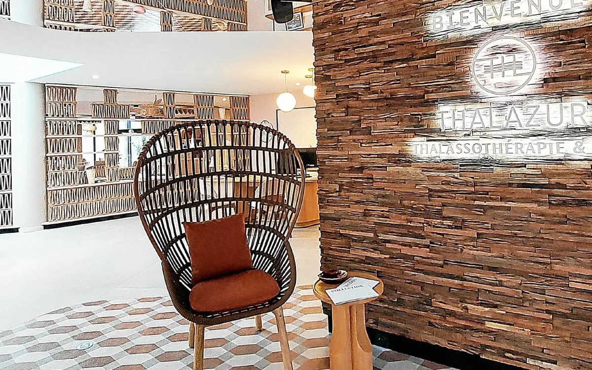 The reception area at Thalazur Carnac, with its wooden wall and rattan armchair