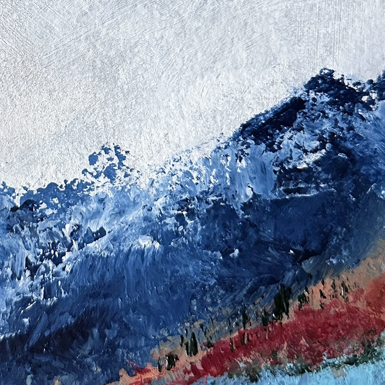 Close-up of textured acrylic brushwork forming deep blue mountain peaks in an abstract landscape painting.