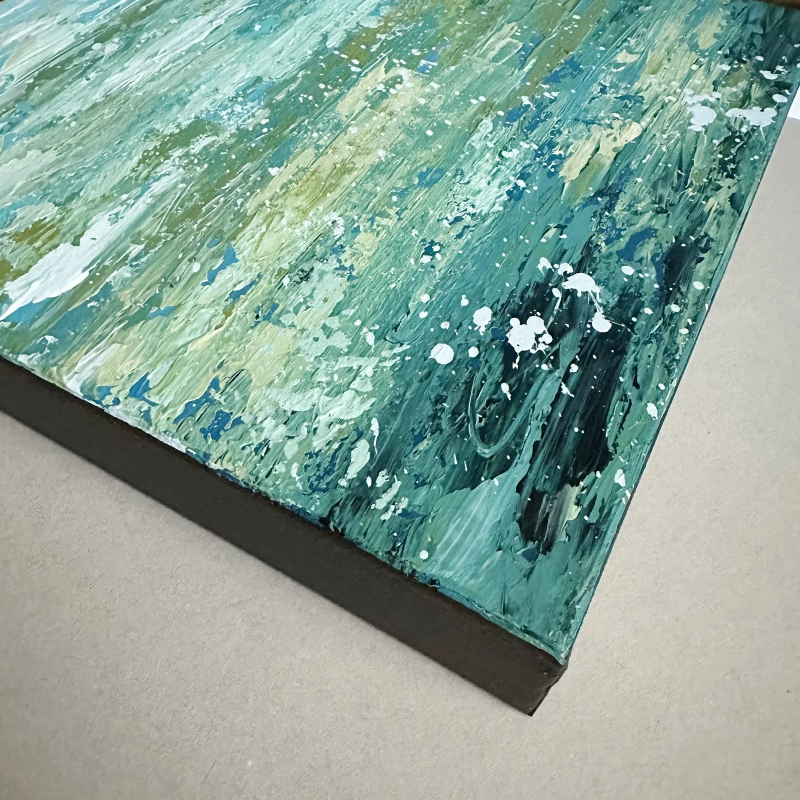 Corner detail of gallery-wrapped canvas green water painting.