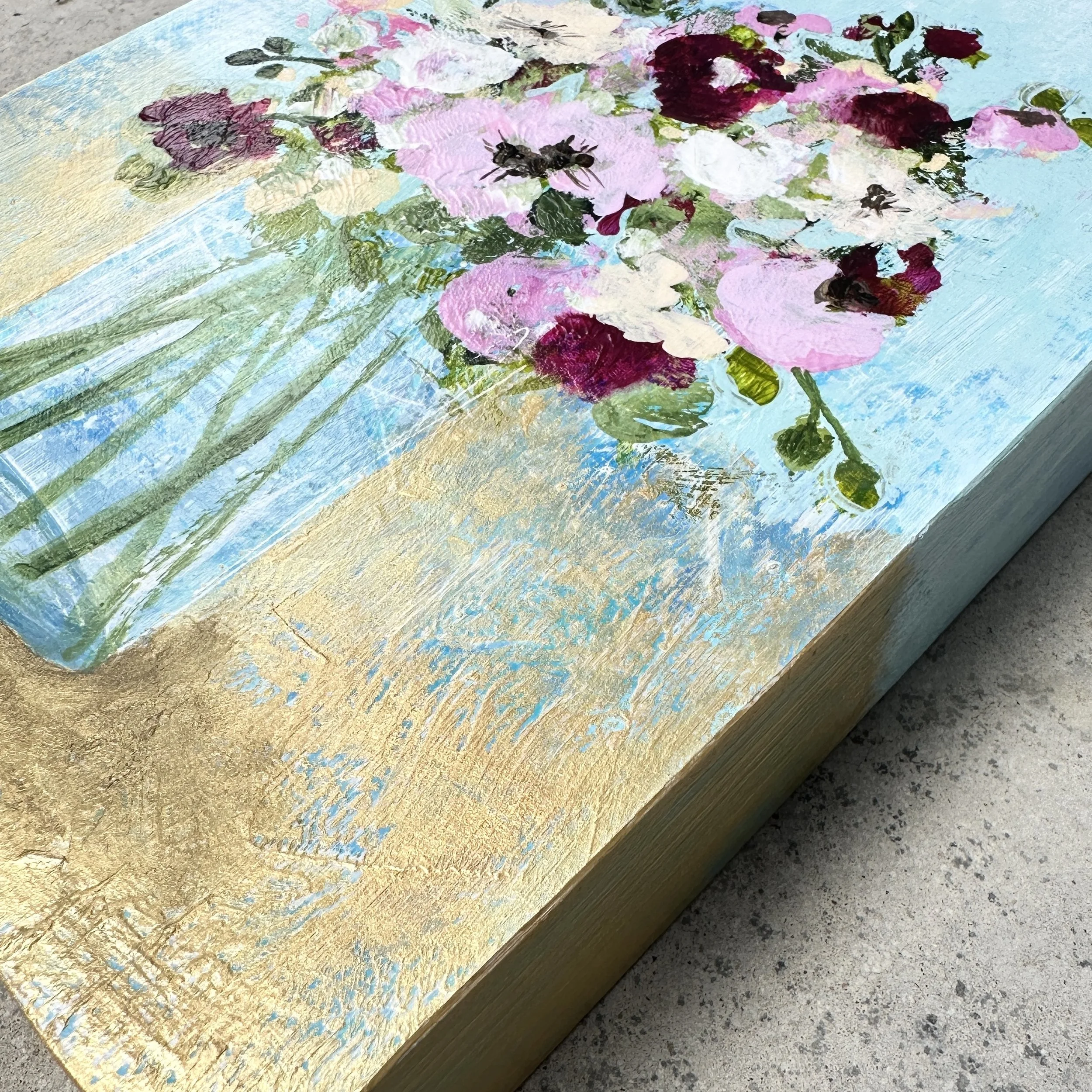 Side view of a floral painting on cradle board.