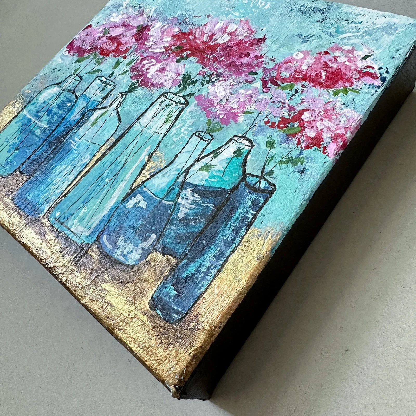 Close-up view of a bottlescape floral mini painting.