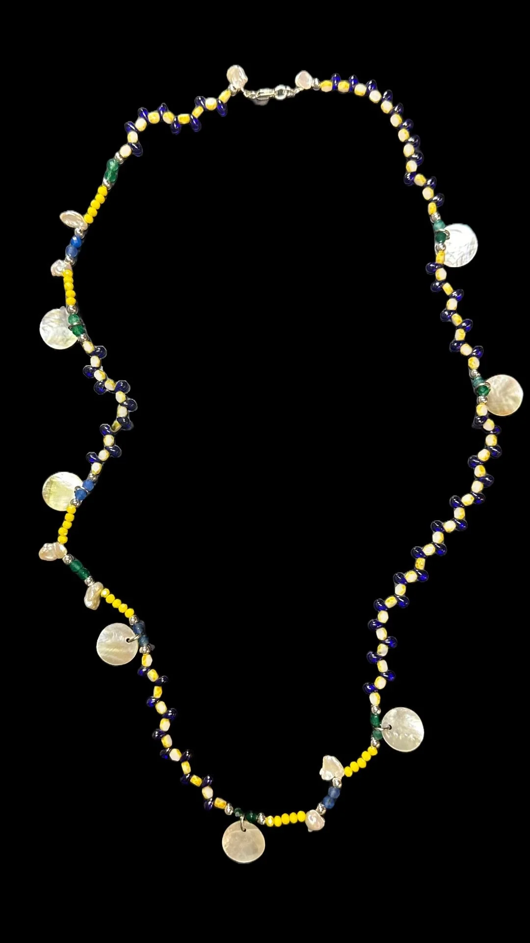 Colorful beaded necklace with yellow, blue, green, and pearl-like beads and discs, set against a black background.