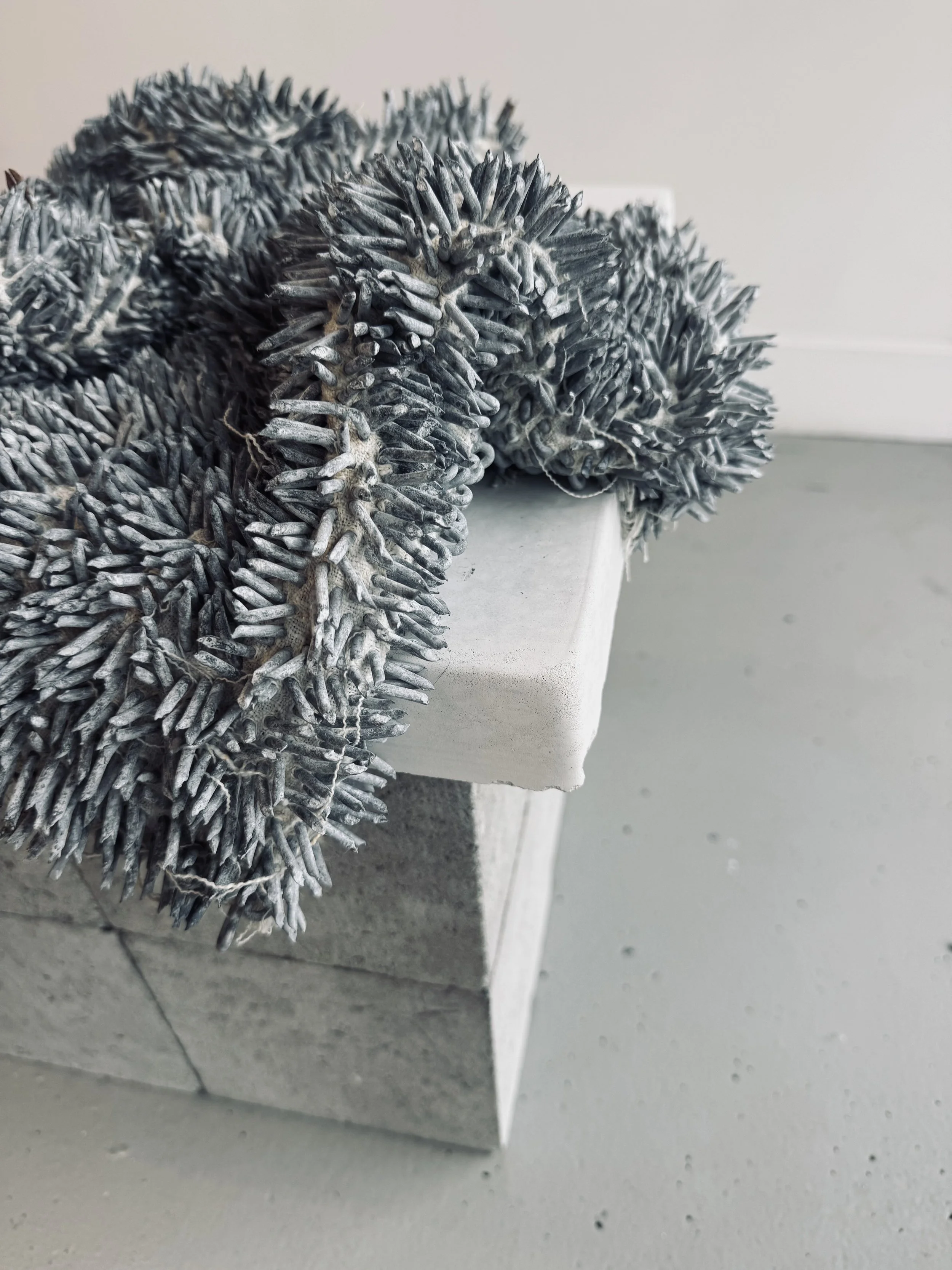 'un(home)', 2022
Fencing staples piercing a homemade linen pillowcase, plinth from stone paver and lesser blocks. 
Approximate dimensions 70 x 50 x 50cm. Installation view. Exhibited as part of the 'Filaments' exhibition at DrawSpace, Sydney. 