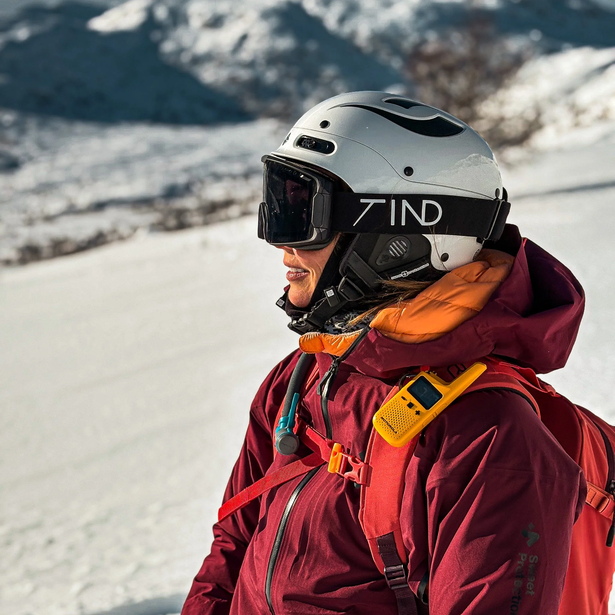 Person med hjelm og skibriller iført rødt jakke, på snødekt fjell. Tind Eyewear. Ski briller. Norge.