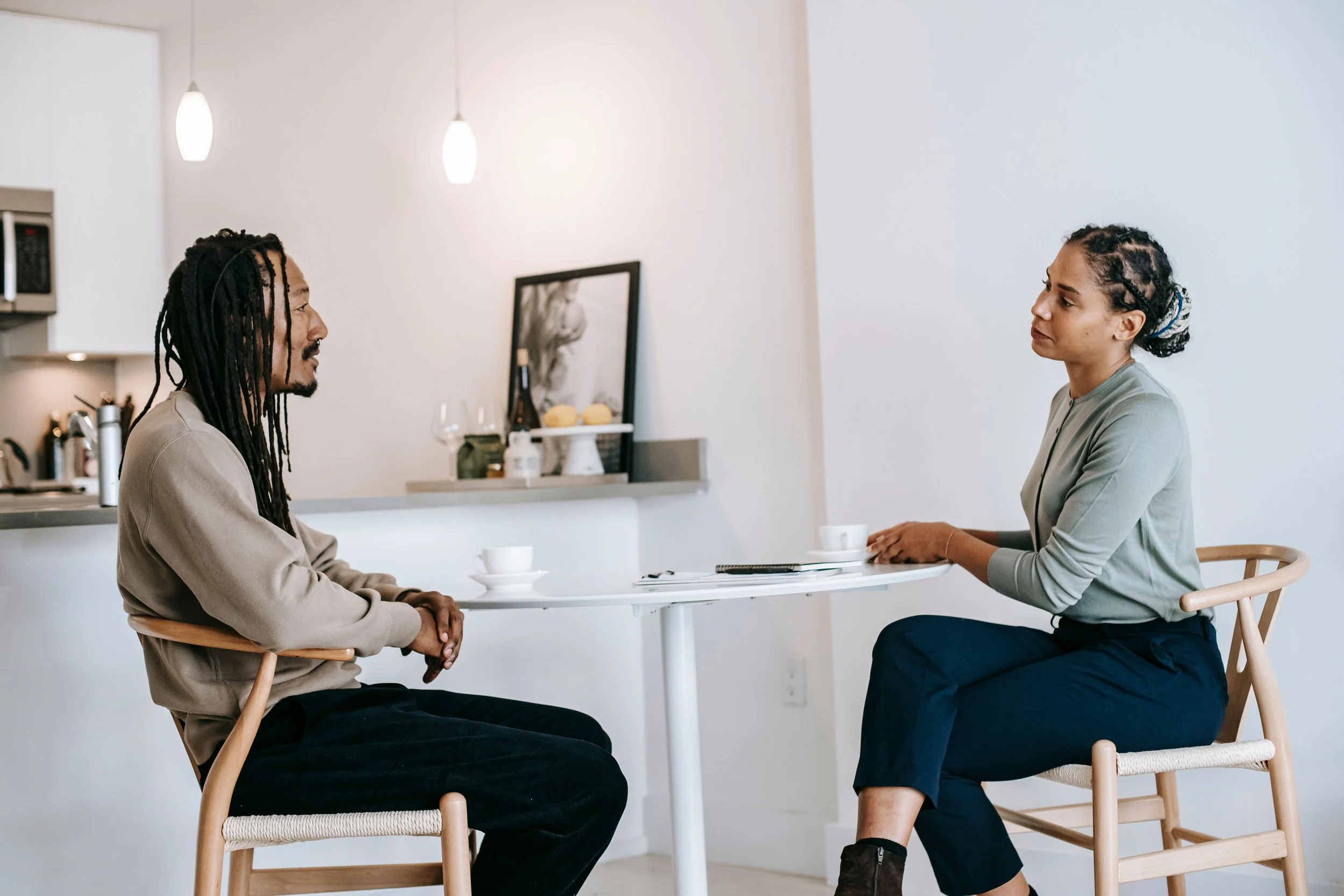 Two people facing each other across a table during a conversation.