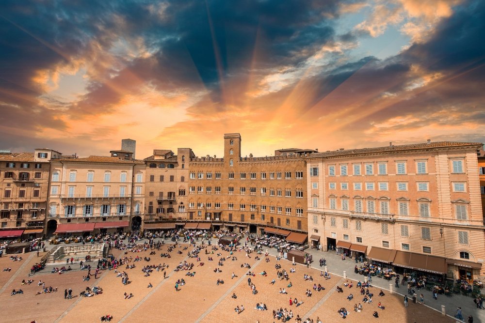 Main square in Siena Italy, with people gathered at all the restaurants around the perimeter