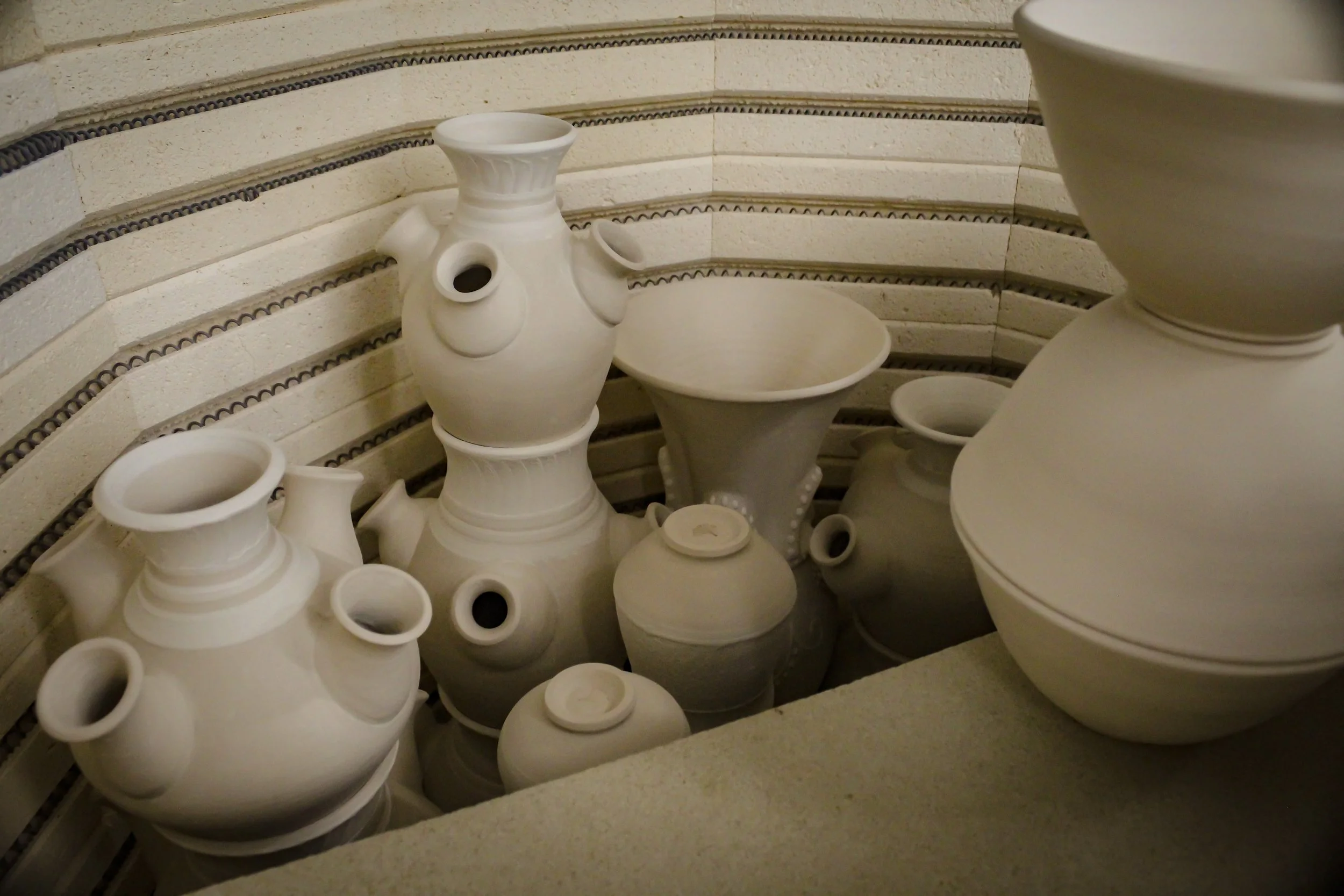 An image of the inside of a kiln packed with vases to be fired