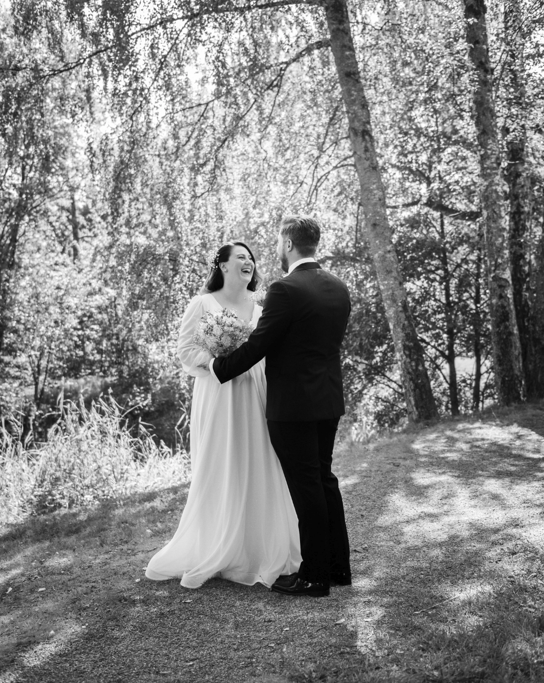 Brudepar i svart-hvitt som ler sammen i skogen på Rosanes i Færder, et ekte og dokumentarisk bryllupsøyeblikk.