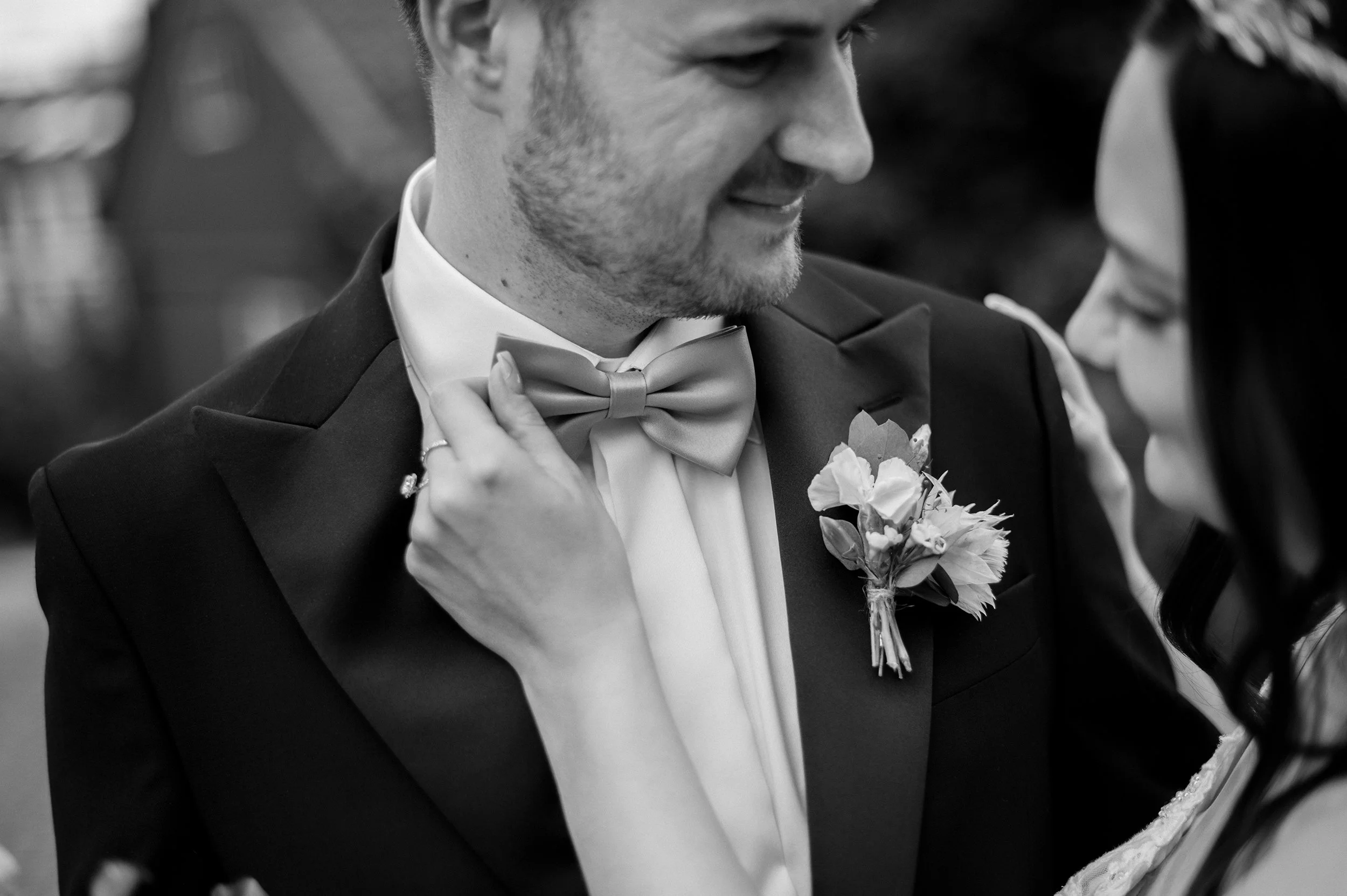 Nært dokumentarisk bryllupsfoto av brud som justerer brudgommens sløyfe, et autentisk øyeblikk fylt med varme i Oslo.