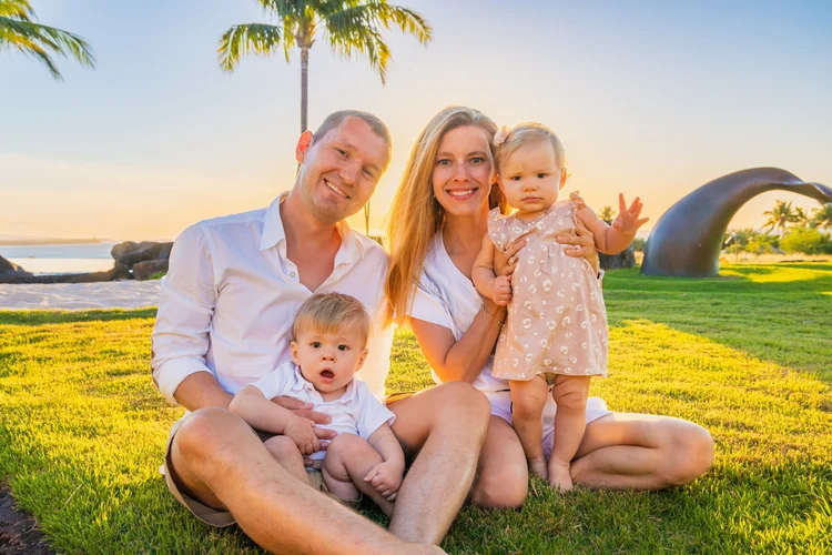 A family of four sitting together on the grass at sunset