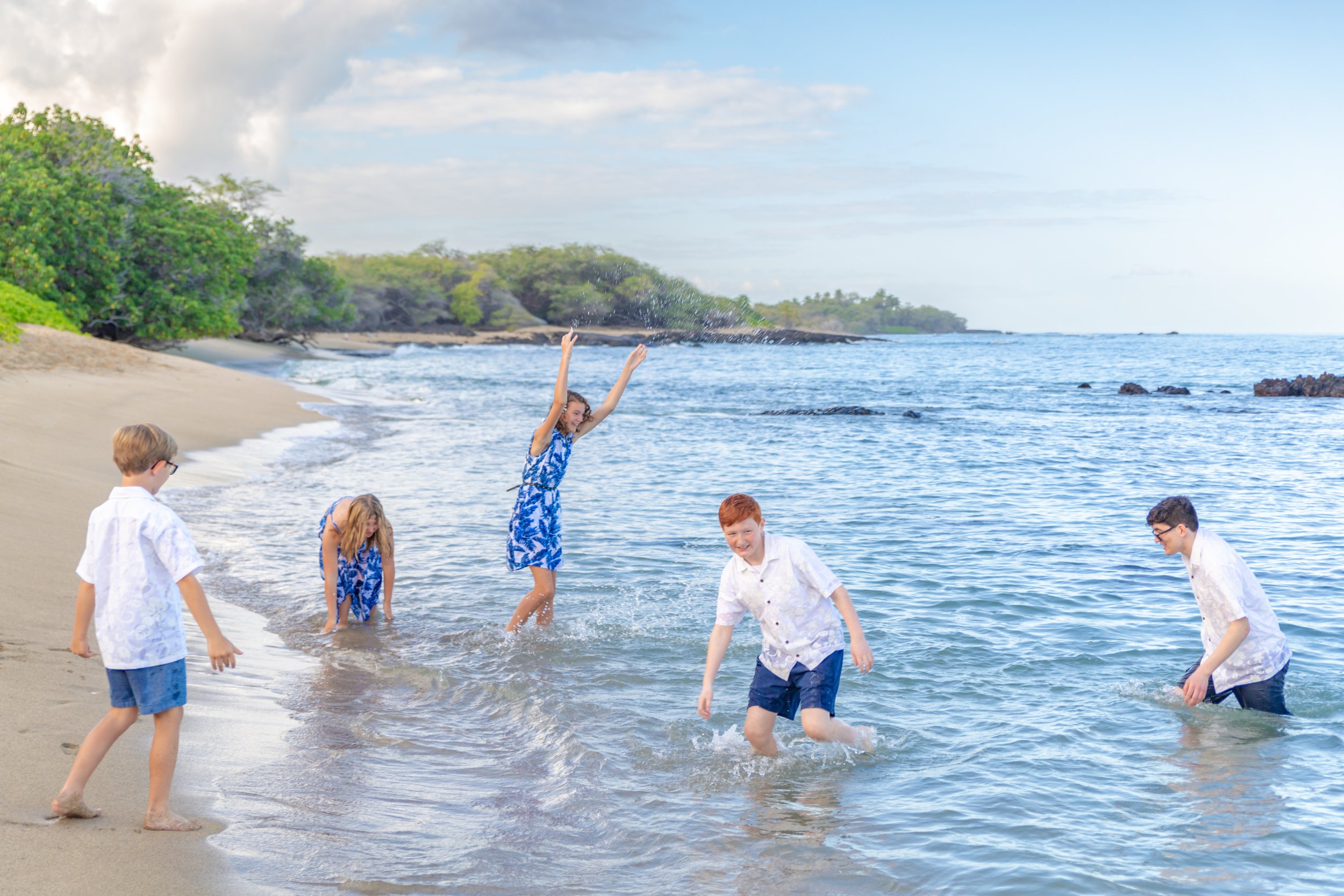 Children playing and splashing in the ocean at the beach on a sunny day.