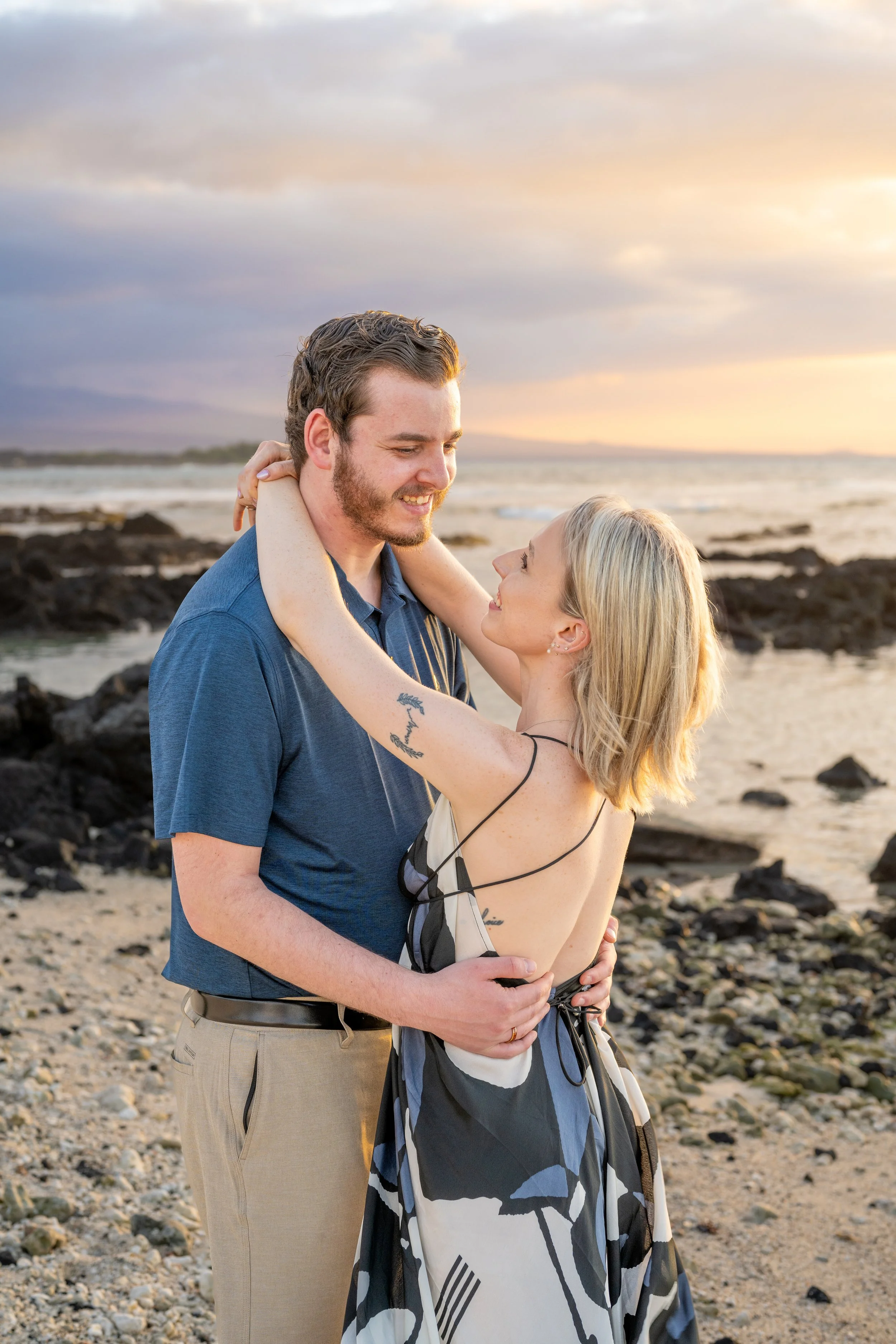 A couple dancing and smiling on the beach during a sunset.