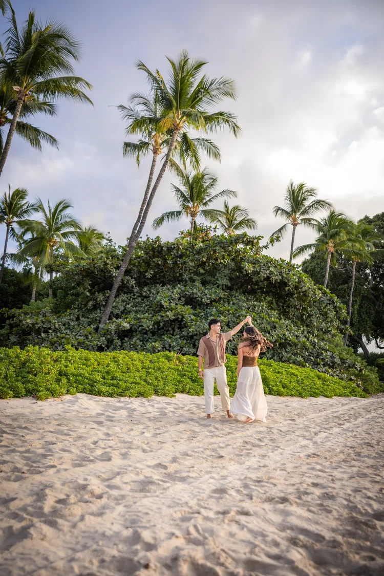 A couple under the palms at the edge of the sand