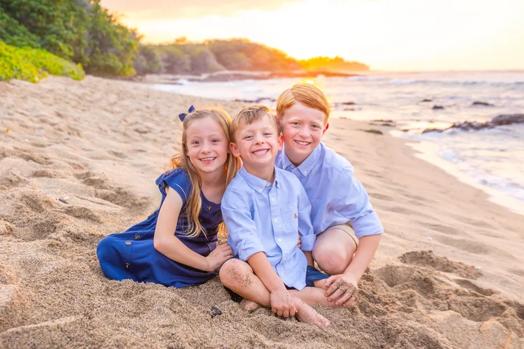 Three brothers and their baby sister sitting together on the lawn