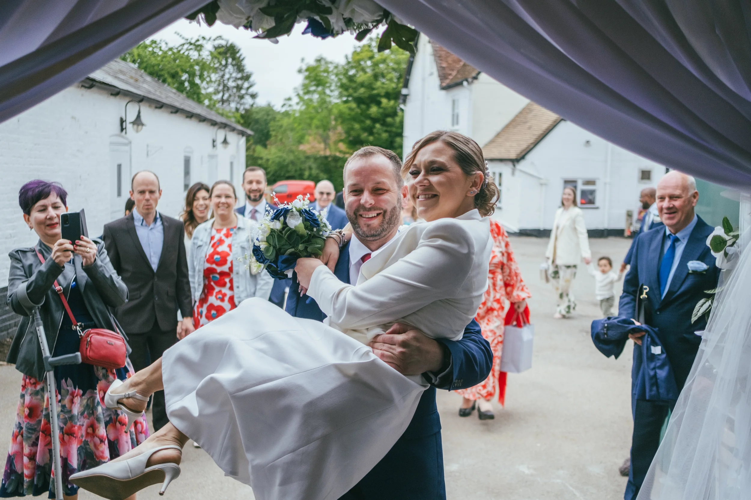photograph of groom carrying bride after ceremony on wedding day