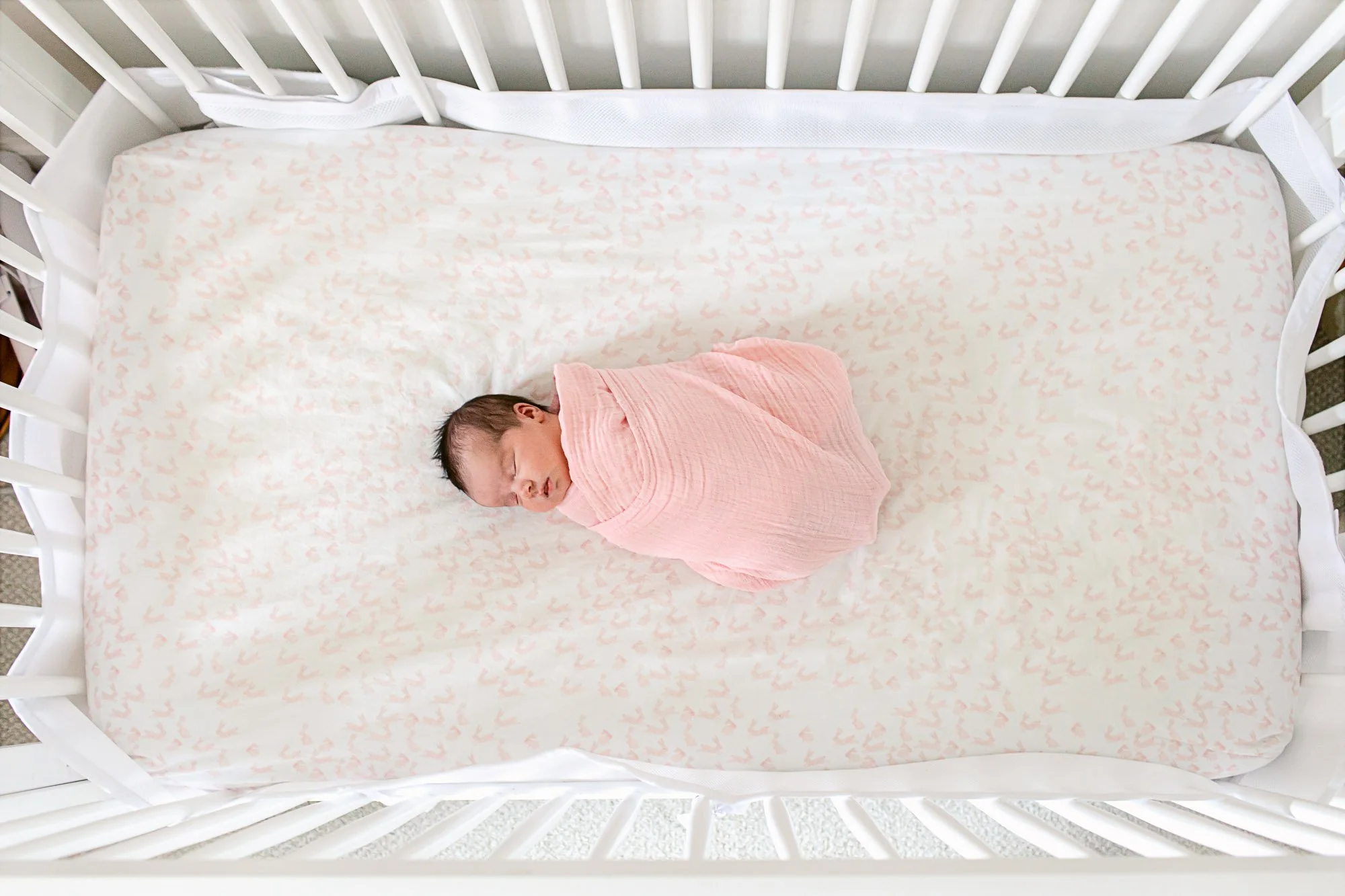 Overhead image of baby girl sleeping in her crib