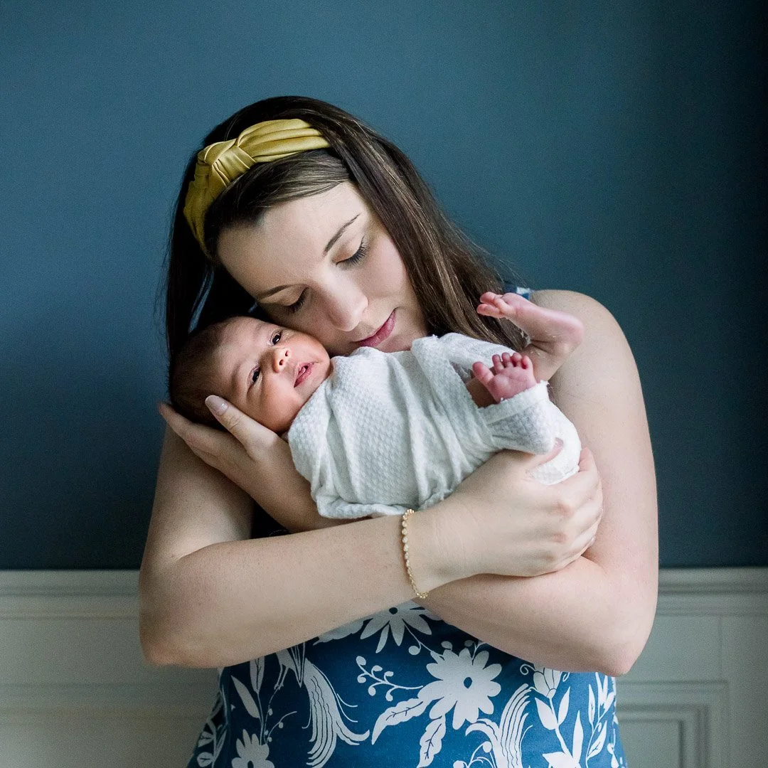 Mother cradling newborn baby girl against her cheek
