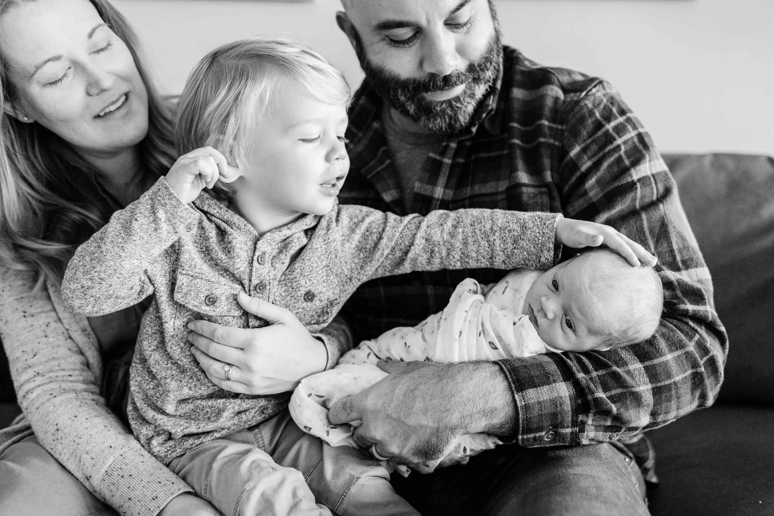 Little boy reaching out to newborn sister