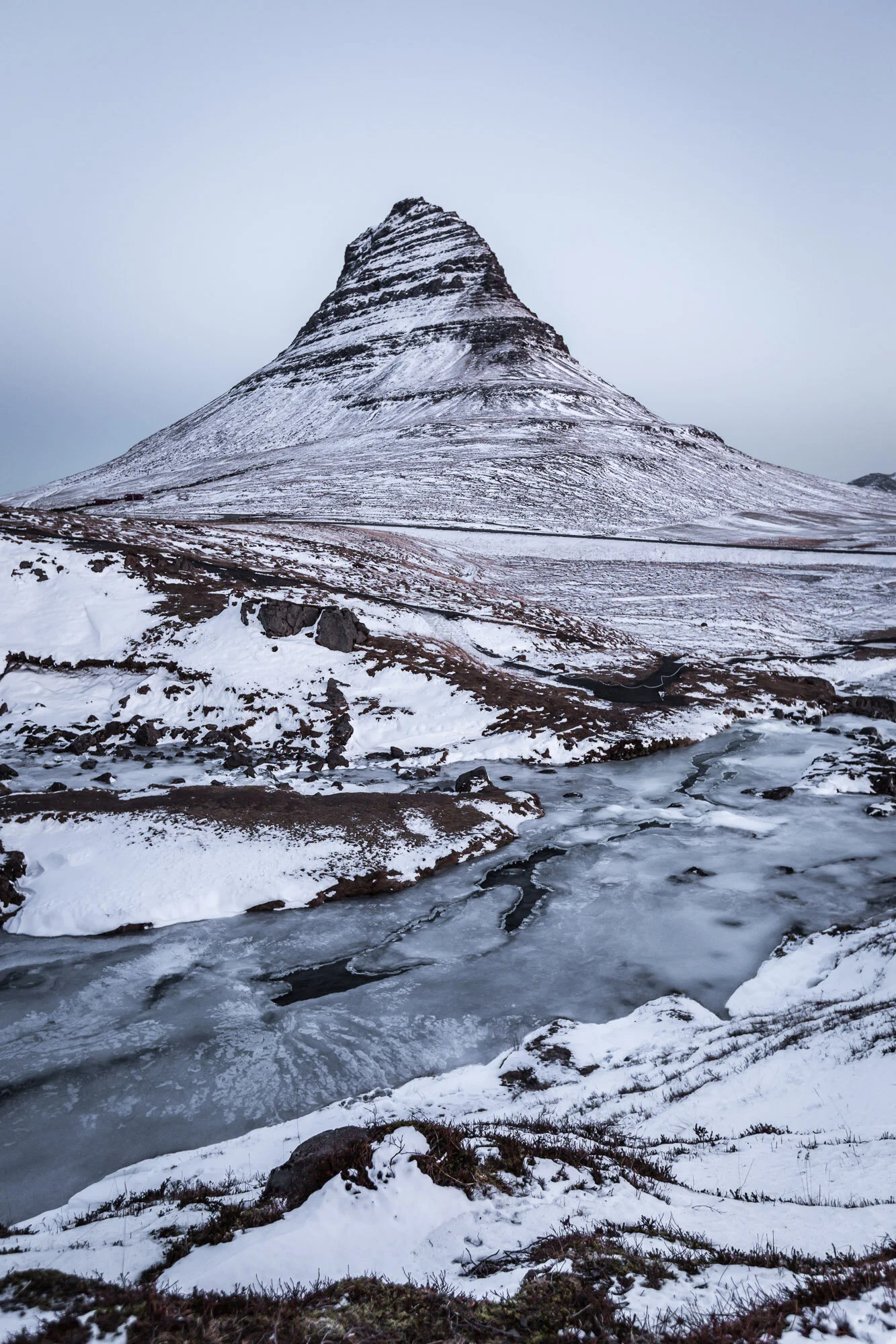 Kirkjufell mountain in winter with frozen waterfall in foreground, Iceland