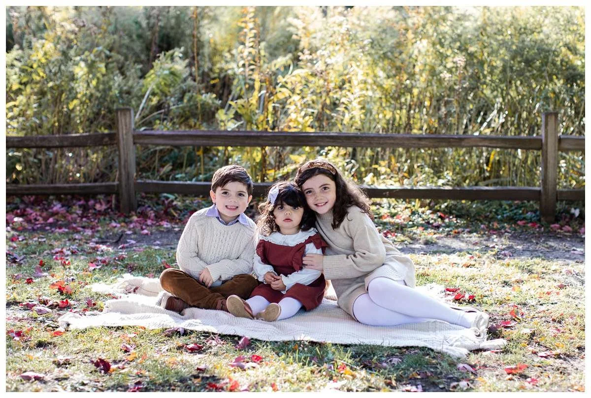 Fall photo of three siblings sitting on a blanket at Winnemac Park in Chicago