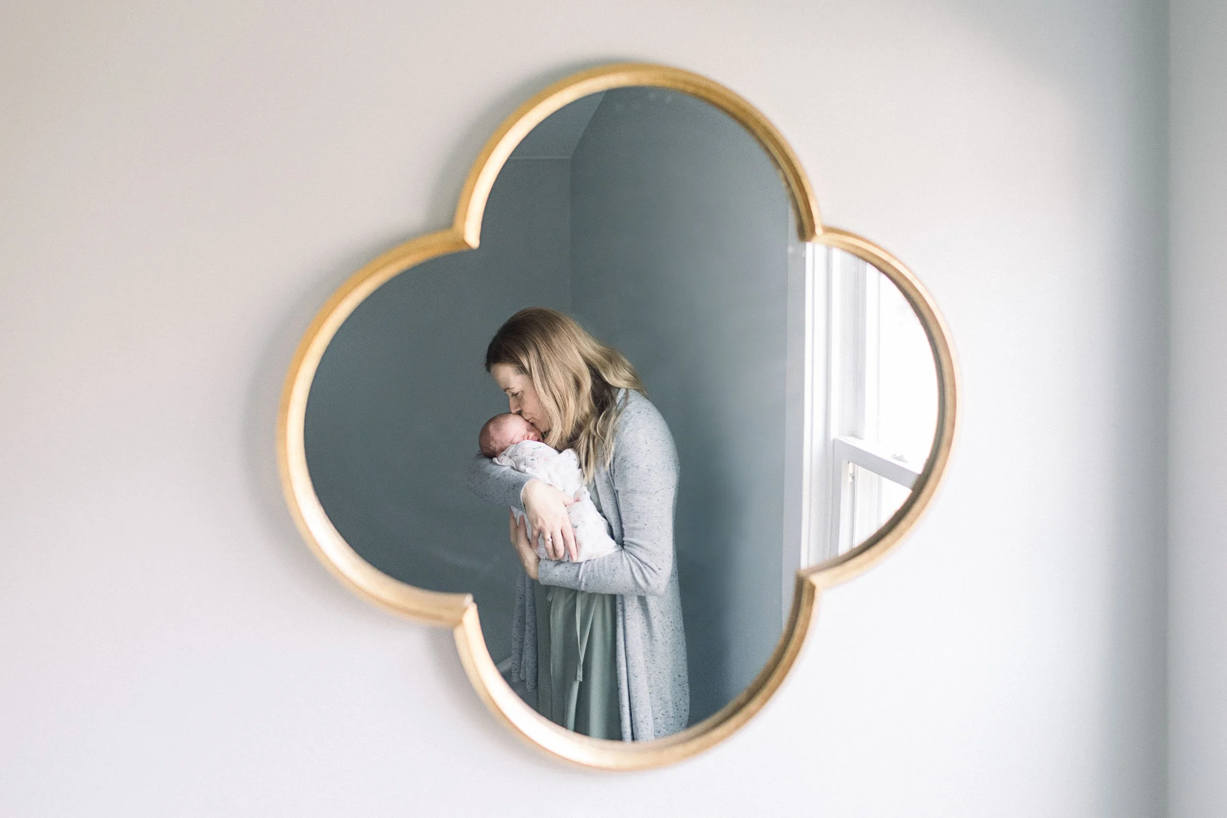 Mirror reflection of mother kissing newborn