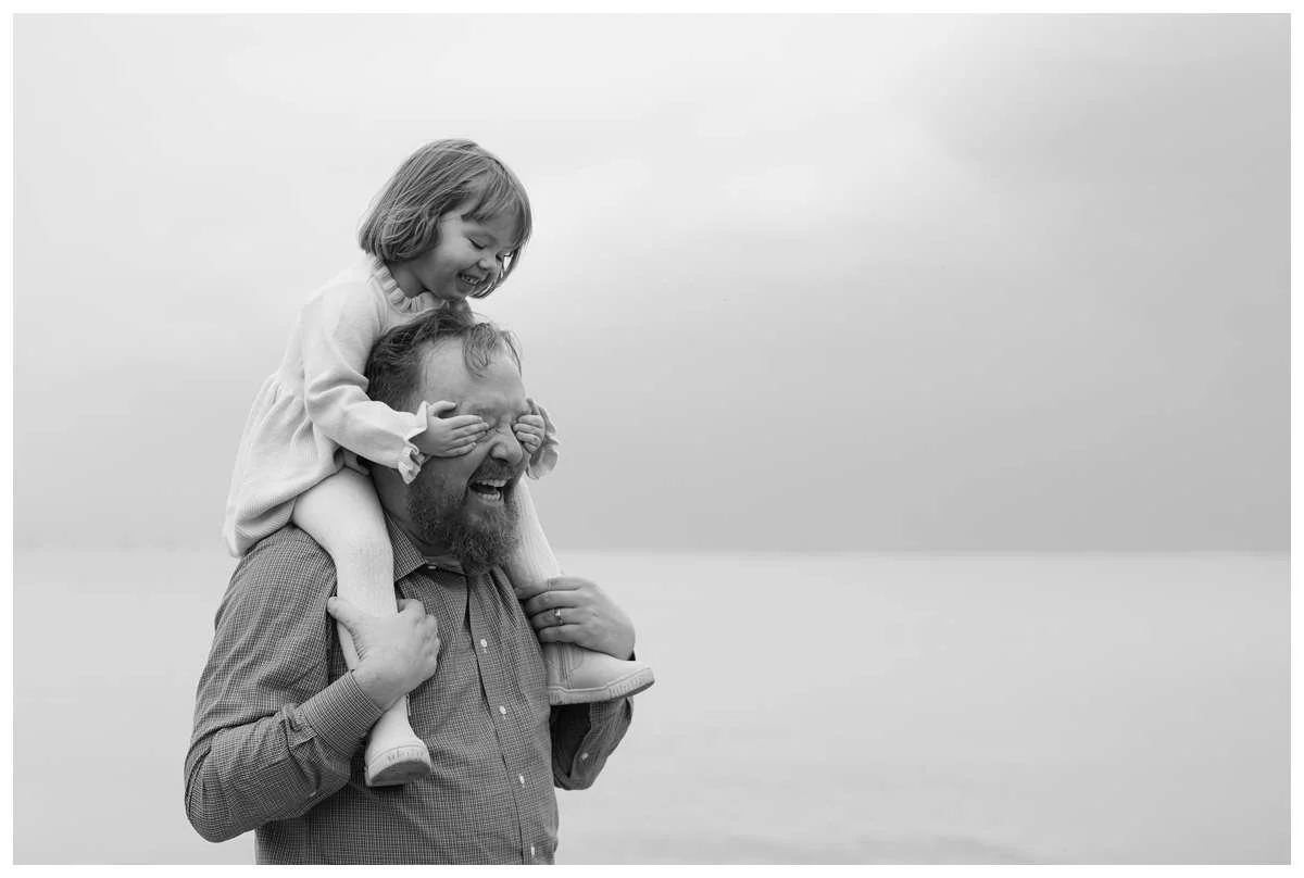 Little girl on dad's shoulder and covering his eyes with her hands