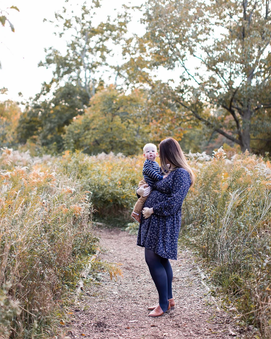Pregnant woman holding baby boy during Chicago Fall Family Session