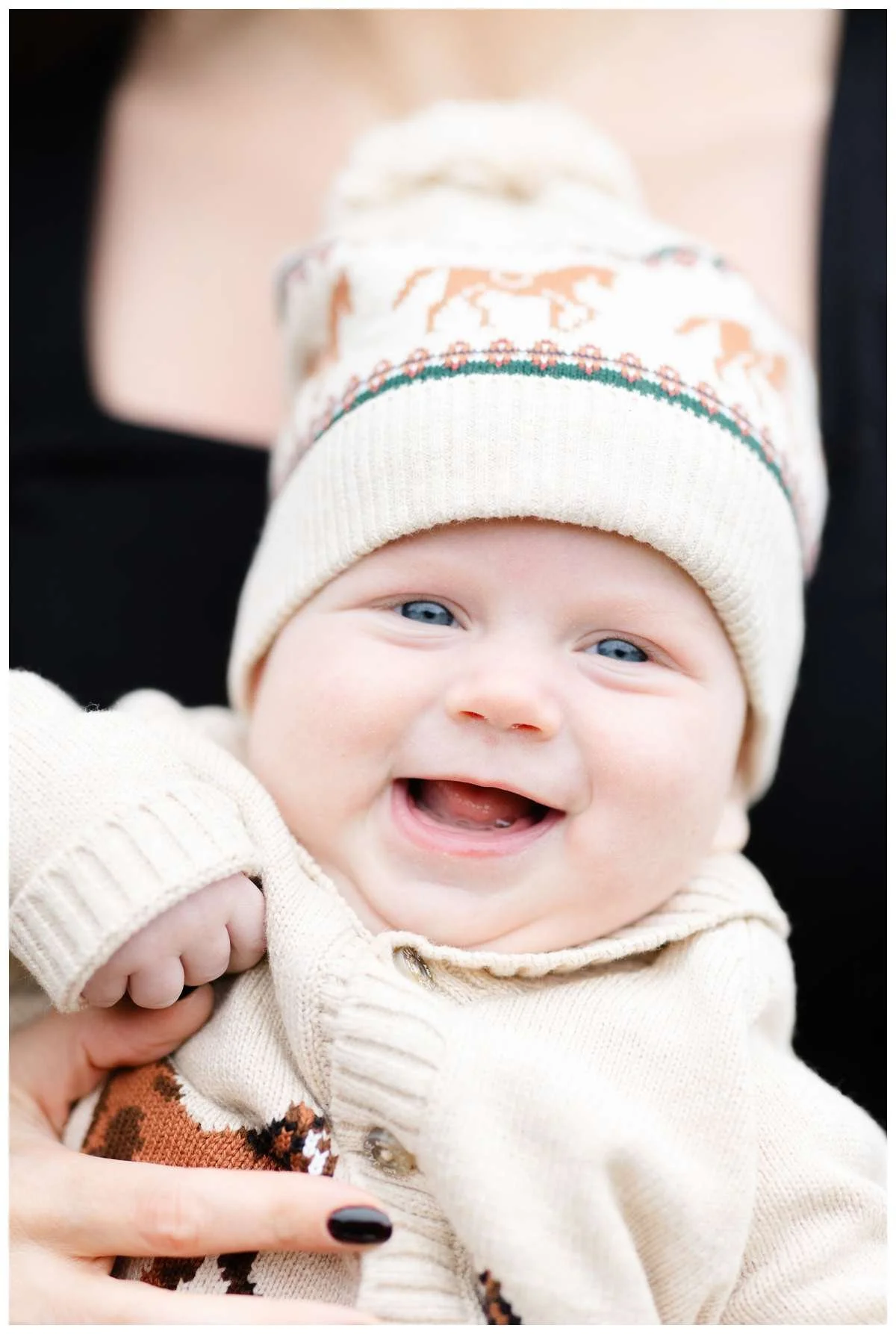 Joyful face of baby boy wearing cozy sweater and beanie