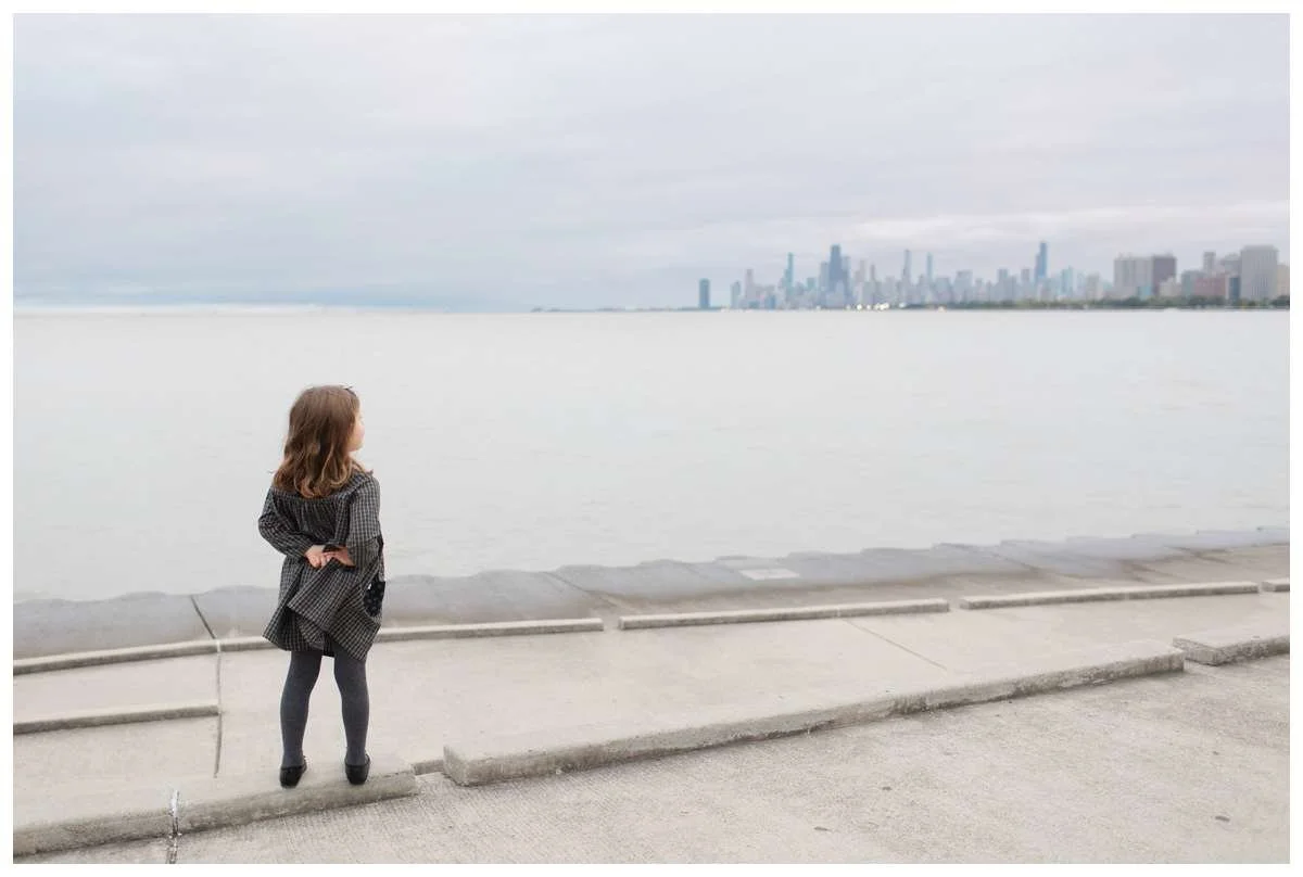 Little girl with back to the camera and hands behind her back starting at Chicago's skyline