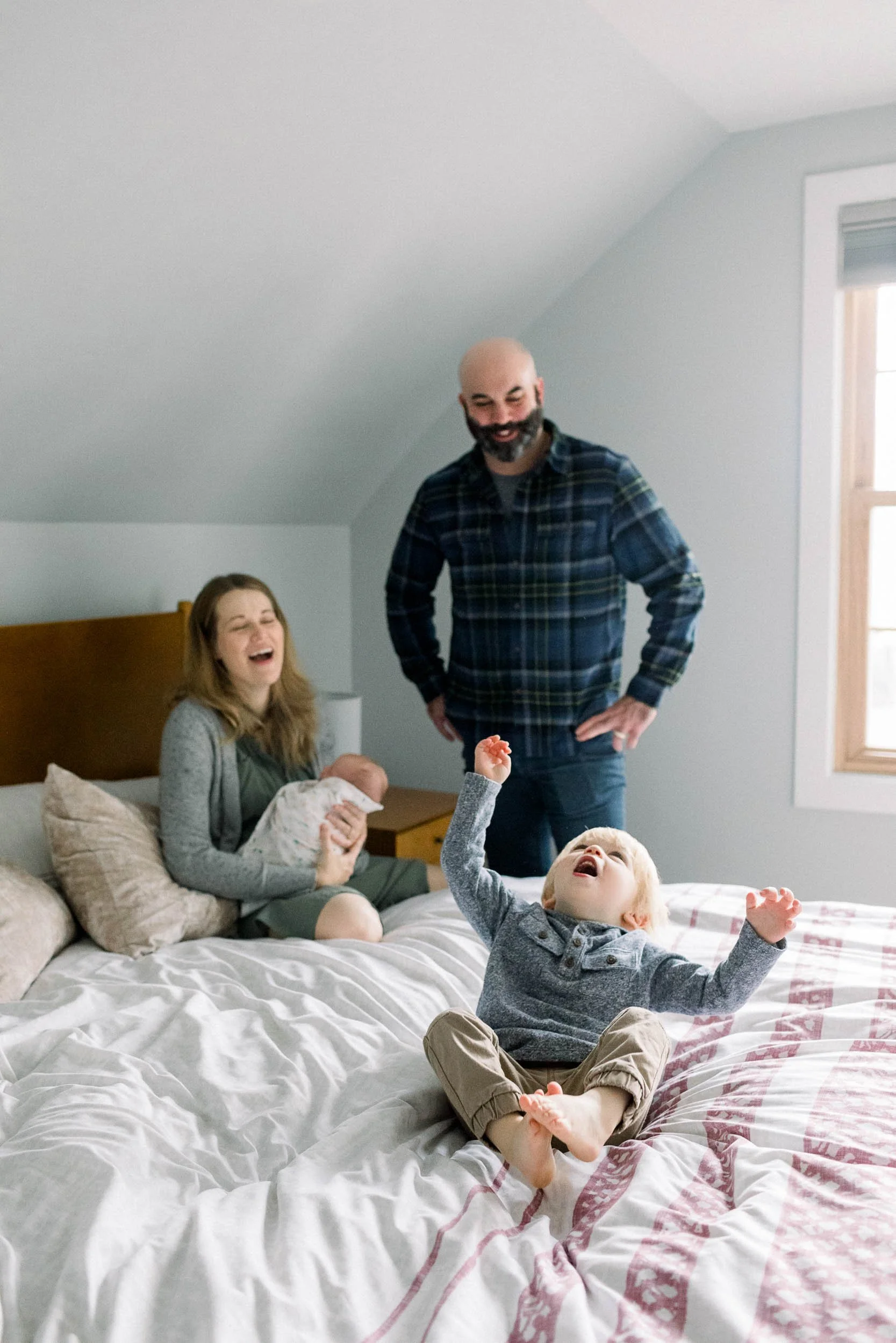 Lifestyle newborn family session with toddler playing on parent's bed