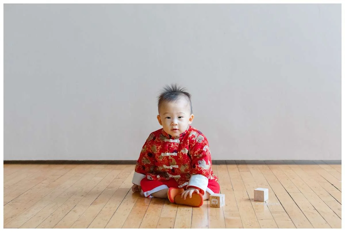 One year old boy dressed in traditional Chinese outfit and posing for a studio photograph