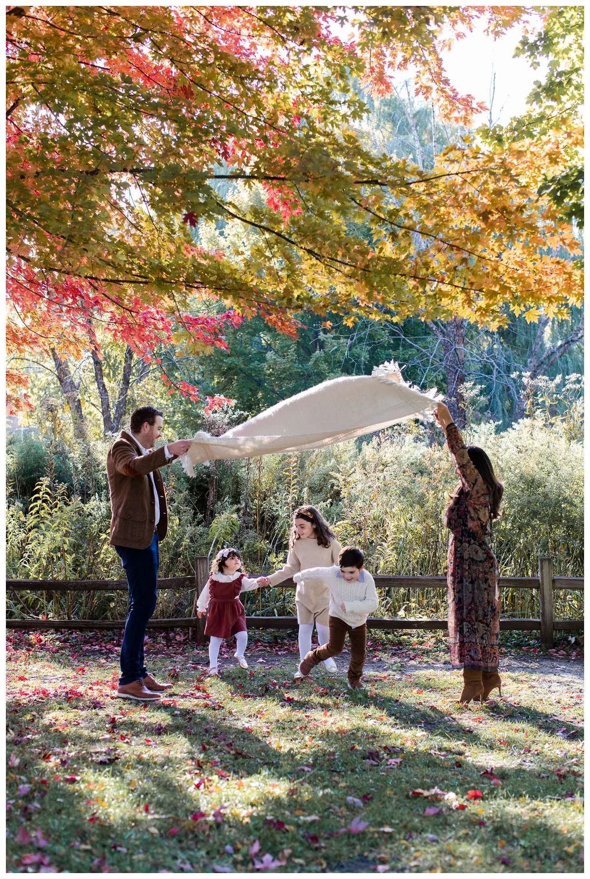 Parents raising blanket on air while three kids run under it by Chicago Fall Family Photographer