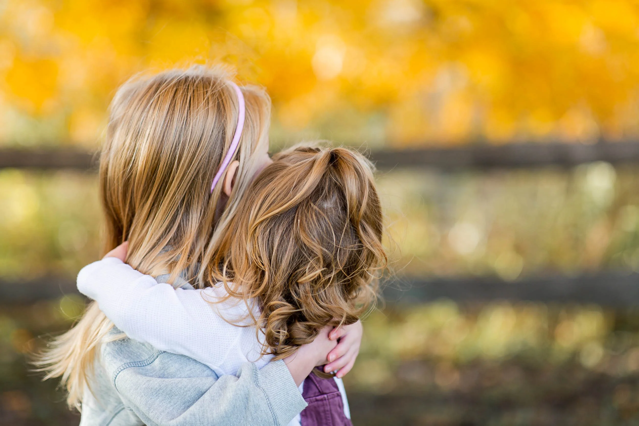 Back of young sisters hugging each other