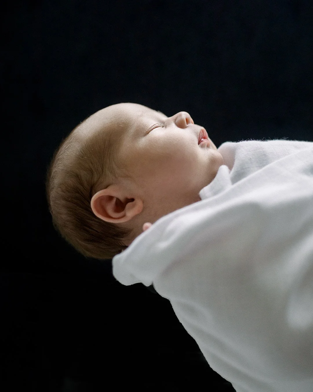 Profile image of baby boy against black background