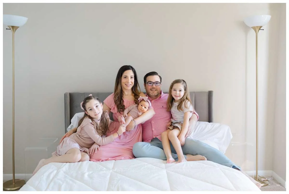Parents with three girls sitting on their bed and smiling by Chicago Photographer